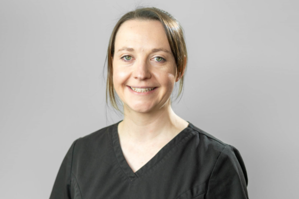 woman smiling against grey background for a headshot