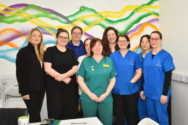 a group of veterinary women standing together in front of a colourful wall for a photo
